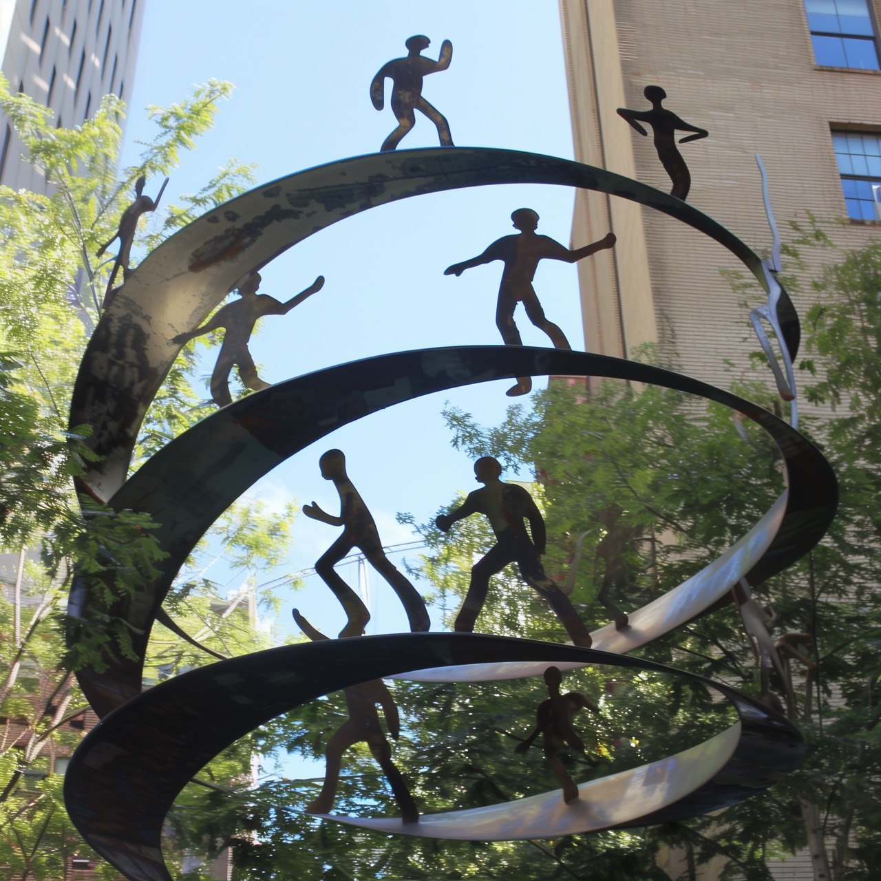 This Is How Time Works: outdoor metal sculpture with curved reflective bands and silhouetted figures